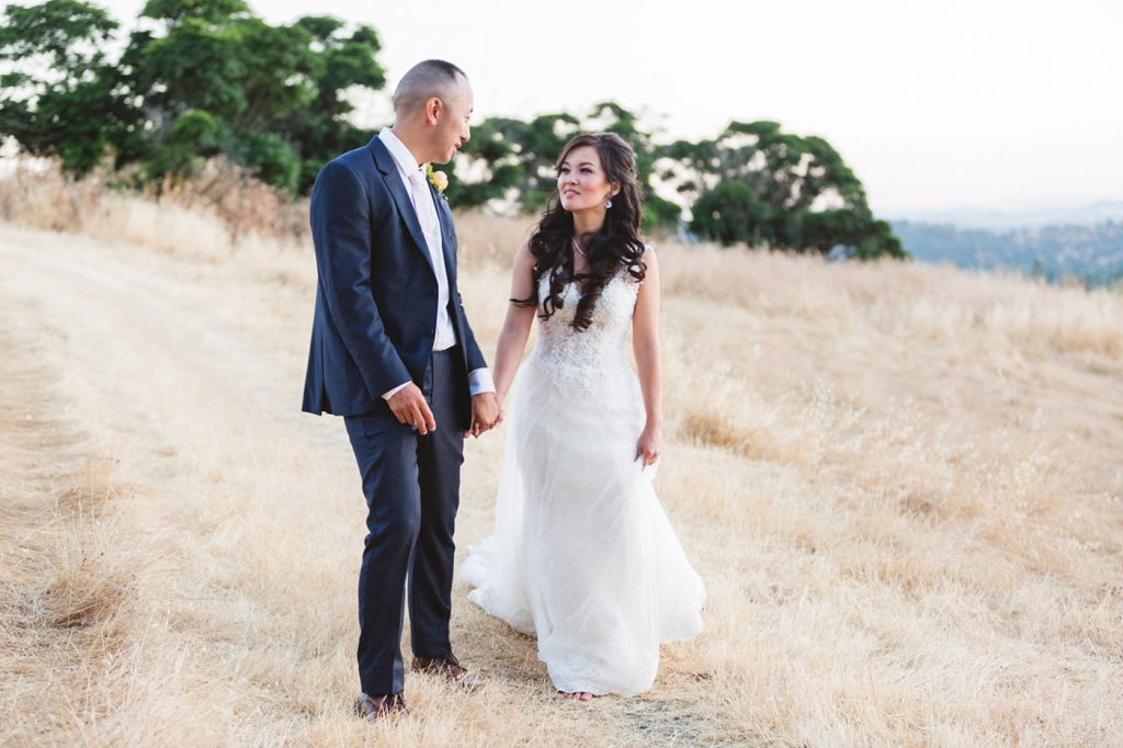 marrying couple walking in dry grass at intimate bay area wedding