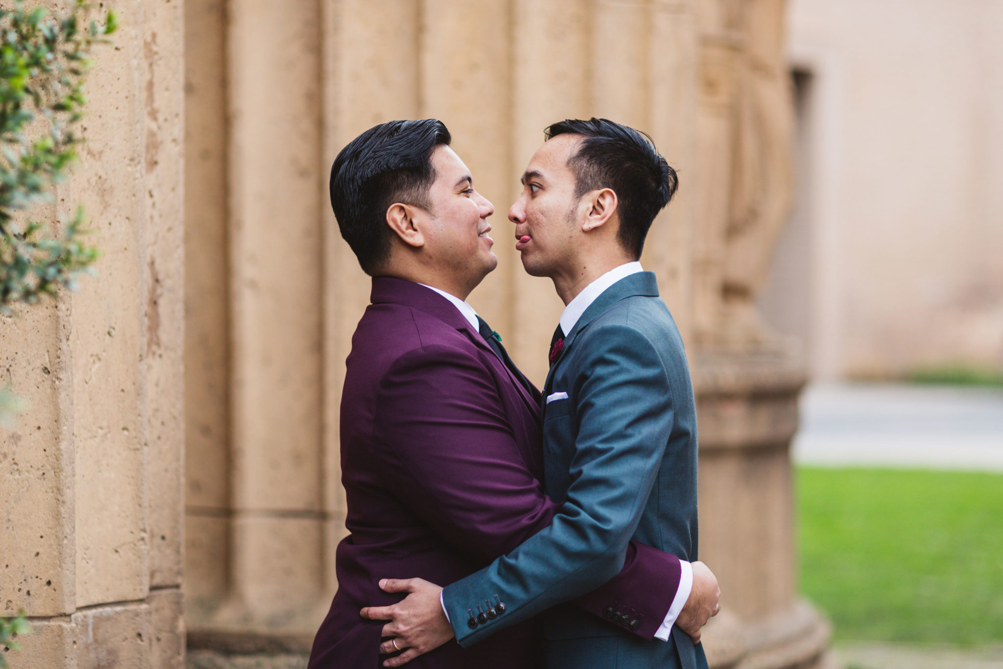 two grooms acting goofy in the palace of fine arts at their wedding