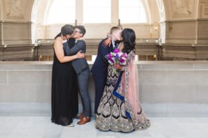 two LGBTQ+ couples kissing at San Francisco City Hall