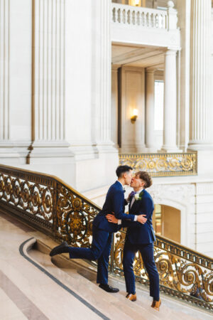 LGBTQ+ wedding couple kissing on grand staircase